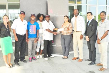 Guyana Marriott’s Director of Sales and Marketing, Denisse Olivo handing over the sponsorship cheque to Leslie Blacks yesterday in the presence of athletes and staff of the hotel. (Orlando Charles photo)