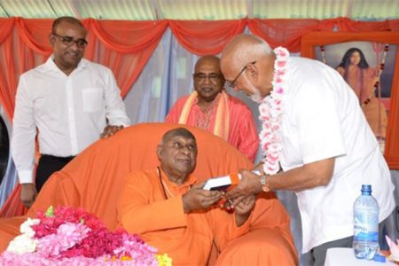 Swami Vidyanandaji Maharaj presents a copy of his biography to President Donald Ramotar as former President Bharrat Jagdeo (left) looks on. (GINA photo)