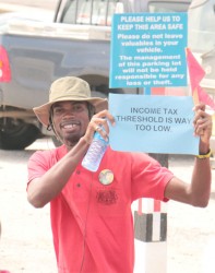 A member of the University of Guyana Senior Staff Association and University of Guyana Workers’ Union delegation highlights one of the workers’ concerns during yesterday’s Labour Day march in the city. (Arian Browne photo)
