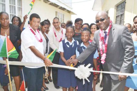 Chief Education Officer Olato Sam (at right) and Region Four Chairman Clement Corlette during the cutting of the ribbon to commission the new wing at the Lancaster Secondary School. (Government Information Agency photo) 