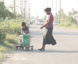 Flashback: Bennita Kissoon fetching water, aided by her son in February. 