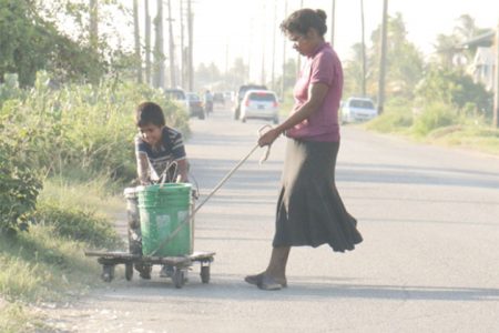 Flashback: Bennita Kissoon fetching water, aided by her son in February.
