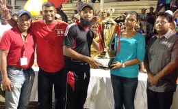 The daughter of Imran and Sons hands over the winning trophy and cash incentives to Assad Fudadin, captain of the Berbice team in the presence of members of the organising committee and Minister of Finance Dr Ashni Singh (far right).
