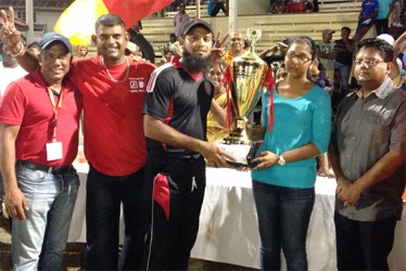 The daughter of Imran and Sons hands over the winning trophy and cash incentives to Assad Fudadin, captain of the Berbice team in the presence of members of the organising committee and Minister of Finance Dr Ashni Singh (far right).