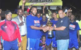 Sparta Boss Captain Morgan Chalmers collecting the championship trophy from Guyana Beverage Company Managing Director Robert Selman (right) following the conclusion of the event while Tournament Coordinator Troy Mendonca (left) of the Petra Organization and other members of the winning team look on  