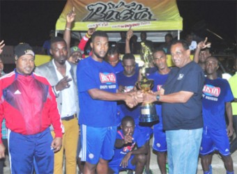 Sparta Boss Captain Morgan Chalmers collecting the championship trophy from Guyana Beverage Company Managing Director Robert Selman (right) following the conclusion of the event while Tournament Coordinator Troy Mendonca (left) of the Petra Organization and other members of the winning team look on   