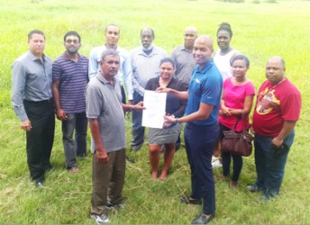 GFF Normalization Committee Chairman Clinton Urling (right) displaying the signed 30 year lease contract with the Eccles/Ramsberg Neighborhood Democratic Council (NDC) for the Providence Community Centre Ground while other members of the GFF Secretariat look on