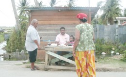 Voters checking to see if their names are on the list of electors at a temporary booth manned by their party agents before going into the Fort Ordnance Primary School to cast their votes
