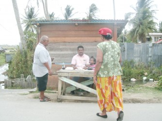 Voters checking to see if their names are on the list of electors at a temporary booth manned by their party agents before going into the Fort Ordnance Primary School to cast their votes 