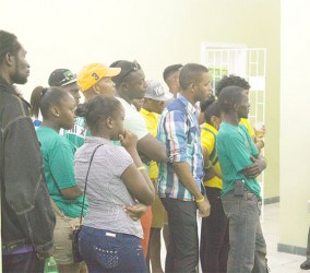APNU+AFC  supporters watching the GECOM press conference yesterday at its Crown and Albert Sts office. 