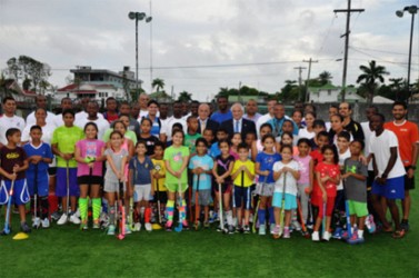 FIH President Leandro Negre (centre-right) and PAHF President Alberto Budeisky (centre-left) posing with members of the Guyana national men and women hockey program as well as youth players of the GCC Academy at their Bourda training facility.