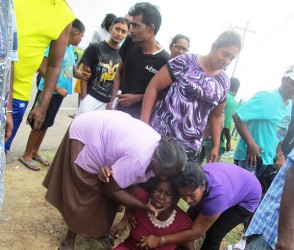 The mother of Deonarine Ramsarran being consoled by relatives at the scene.