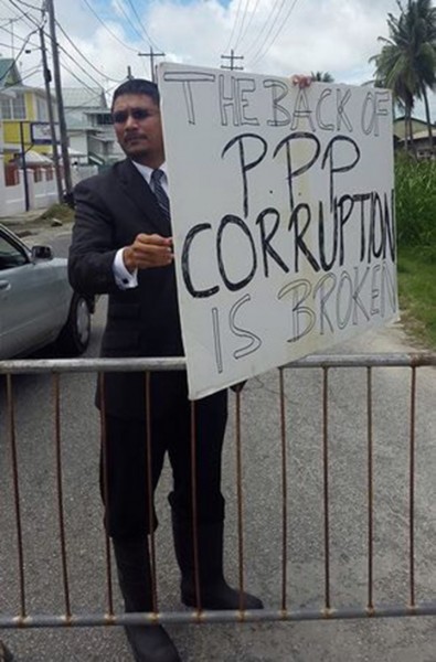 Gino Persaud holding up his placard yesterday. (Gordon Moseley photo) 