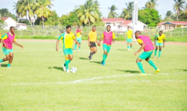 Central defender Adrian Butters (red) in the process of challenging midfielder Vurlon Mills for possession of the ball just outside the 18-yard box during their inter-squad practice match. 