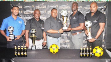 Tournament Coordinator Troy Mendonca (centre) receiving the championship trophy from Guinness Brand Manager Lee Baptiste during the launch of the Guinness Greatest of the Streets National Championship while other members of the launch party look on. 