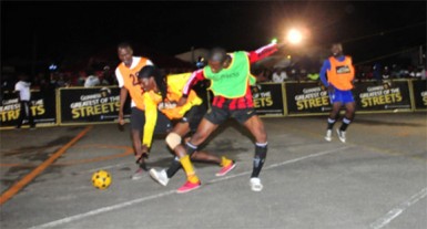 Melanie-B’s Amoniki John (orange) in the process of being fouled by Showstoppers John Waldron (green) during their Guinness Greatest of the Streets National Championship fixture at the National Cultural Center Tarmac