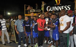 Sparta Boss Captain Devon Millington receiving the championship trophy from Guinness Caribbean Freestyle Champion Mark Taylor (red) while other members of the team, Banks DIH Limited and the Petra Organization look on