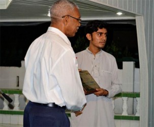 Fazil Azeez’s son (right) receiving the award from President David Granger (ACIC photo) 