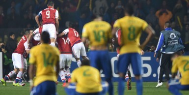 Stunned Brazilian players watch on as Paraguay celebrate their penalty shootout win.