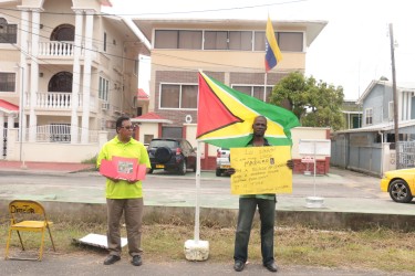 Businessman Don Gomes (left) and another member of the public protesting yesterday outside the Venezuelan embassy against the maritime decree issued by the Venezuelan government. 