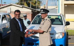 A smiling Police Commissioner Seelall Persaud (right) accepts the keys to 11 new vehicles from Public Security Minister Khemraj Ramjattan. The vehicles, which were handed over yesterday, will be used for patrol purposes in the various police divisions. They were originally intended for community policing groups, but were given to the police force instead in light of its shortage of vehicles.