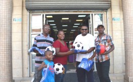 Secretary of the Order and Discipline Football Club Nicola Lambert receives the donation of equipment from Rajan Tiwari of Payless Variety Store, (second right) as coach Mark DeBarros (left) and club captain, Ken Wilson look on.