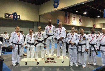 World Martial Arts champion Professor Ken Danns flanked by the second and third placed finishers on the podium at the recent Martial Arts tournament in the USA.