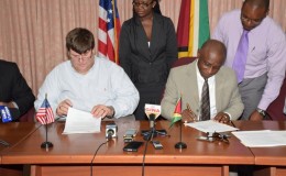 Minister of Foreign Affairs Carl Greenidge and Chargé d’Affaires of the US Embassy Bryan Hunt signing yesterday (GINA photo)