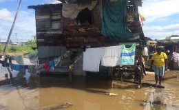 A small house along the Railway Embankment road amidst floodwater.
