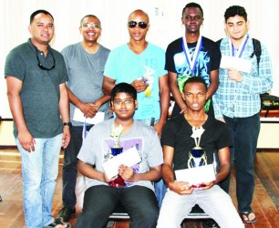 FIDE Candidate Chess Master Anthony Drayton (right, seated) and Joshua Gopaul (left, seated) are the senior and junior winners respectively of the recent Caricom seven-round rapid tournament. Drayton, who represented Guyana at last year’s Tromso Chess Olympiad, scored seven wins from his seven games of the competition which was held at the National Resource Centre. He played with verve. Gopaul, on the other hand, will represent Guyana at next month’s Guyana games. Standing are the other prize winners of the tournament. Red Cherry’s Loris Nathoo is second from left.