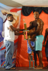  Men’s Physique winner, Emmerson Campbell collecting his first prize trophy from Supligen’s Brand Manager, Treion D’Anjou. (Orlando Charles photo)