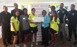 Captain of the Lady Jaguars unit Ashley Rodrigues receiving the sponsorship cheque from Scotia Bank Marketing Manager Jennifer Cipriani while other members of the team and the GFF Normalization Committee look on.