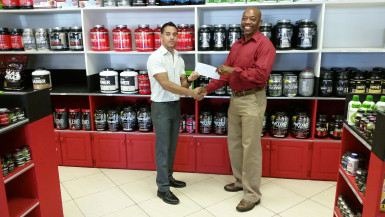  General Secretary of the GAPF, Gordon Spencer receiving the event’s sponsorship from CEO of Fitness Express, Jamie McDonald.