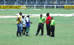The umpires and ground staff chat whilst making one of several inspections. (Orlando Charles photo)