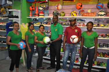 Fruta Conquerors Secretary Daniel Thomas (3rd from right) collecting the donated balls from Colours Boutique representative Shondel Kandar while other members of the company and club look on