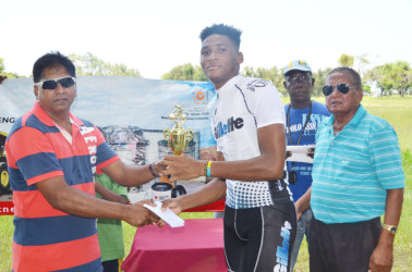 Michael Anthony receiving his rewards from Managing Director of the Nauth’s Motor Spares, Surendra Nauth after biking to victory in the feature 35-lap event of the inaugural Nauth’s Motor Spares 11-race cycle programme yesterday at the National Park.  