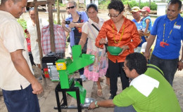Minister Valerie Garrido-Lowe demonstrating the use of one of the four cassava mills. (GINA photo)