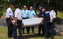 French gendarmes and police carry a large piece of plane debris which was found on the beach in Saint-Andre, on the French Indian Ocean island of La Reunion, July 29, 2015. Reuters/Zinfos974/Prisca Bigot