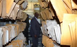 Minister of State Joseph Harmon amid the files at the Land Registry today. (Ministry of the Presidency photo)