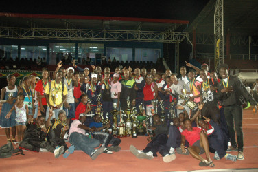 Assistant Commissioner of Police (Administration), Balram Persaud (centre) joins Headquarters yesterday at the National Track and Field Centre at Leonora as they celebrated winning the Police Inter-Division Athletics Championships.