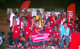 Captain of the victorious Christianburg/Wismar Secondary Tevin Crawford (yellow) collecting the championship trophy from Digicel CEO Kevin Kelly while other team-mates celebrate their fourth consecutive title win over Chase Academy yesterday at the National Stadium in Providence. (Orlando Charles photo)