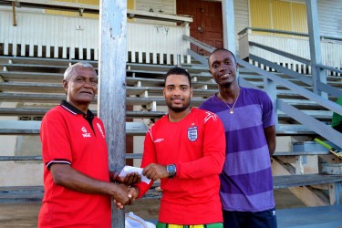 Naushad Mohamed hands over cheque to Rose Hall Town Youth & Sports Club captain Shawn Pereira while Eon Hooper looks on 