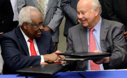 RJR Group chairman, Lester Spaulding (left) and The Gleaner’s Chairman, Oliver Clarke, exchange documents sealing the deal of the merger.
