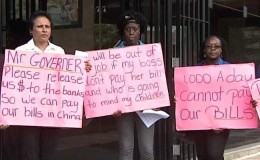 Businesswoman Mary Ramlogan, left, is joined by two of her employees as they hold up placards yesterday during their protest over the inadequate supply of foreign currency outside the Central Bank in Port of Spain. —Photo courtesy TV6