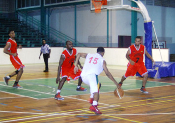 Shelroy Thomas (no.15) of Colts in the process of attacking the rim while being challenged by Ryan Stephney (centre) and Marlon Rodrigues (no.7) of Ravens during their team’s Open Divisional finale at the Cliff Anderson Sports Hall. (Orlando Charles photo)