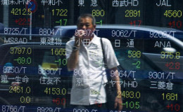 A man looks at stock prices displayed at a board showing market indices in Tokyo July 28, 2015. (Reuters/Thomas Peter)
