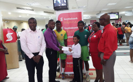 Young Romeo Deonarain receives the sponsorship check from Scotia Bank Business Manager Richard Damon in the presence of his teammates, club President Alfred Mentore and the bank’s executives Karen Harris and Brian Hackett.
