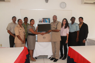 In photo,  Commissioner of Police Seelall Persaud, (fourth from right), is seen receiving the computer from Innovative Mining Company Official Mohini Heera. They are flanked by members of the Help Line’s Steering Committee.   