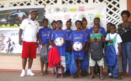 Overseas-based Guyanese and sports enthusiast Lloyd Lashley posing with students and a teacher of the Enterprise Primary School after donating football equipment and school supplies to the institution  