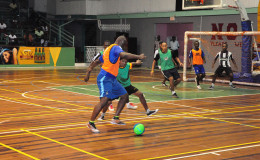 Dennis Edwards (orange) of Sparta Boss trying to maintain possession of the ball while being challenged by a Globe Yard player during his side’s lopsided win in the GT Beer Futsal Championship at the Cliff Anderson Sports Hall. (Orlando Charles photo)